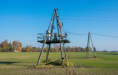 Tahta yüksek voltajlı güç hatları mavi gökyüzüne karşı destekler. Elektrik Sanayi.