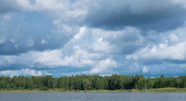Nehir ve orman ufukta manzara. Kümülüs bulutlar gökyüzünde. Letonya doğa. Yaz günü
