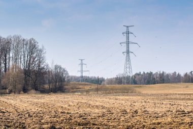 Erken ilkbaharda yüksek voltajlı elektrik hatları ve sürülmüş alanı destekler ile Peyzaj.