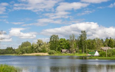 Yeşil ormanlarla çevrili bir göl ile doğal yaz manzara. Mavi gökyüzündeki beyaz bulutlar.