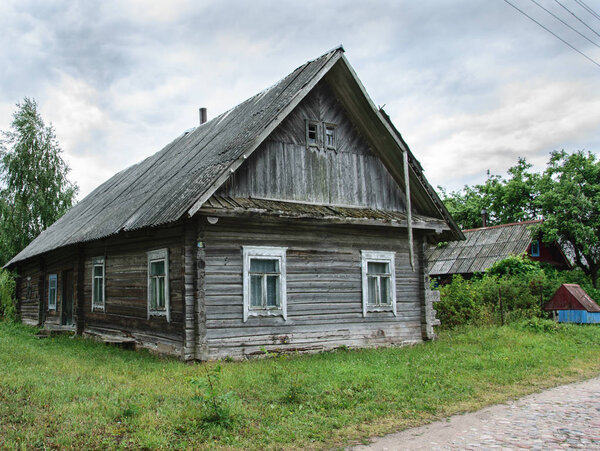Old wooden weathered abandoned house in village.
