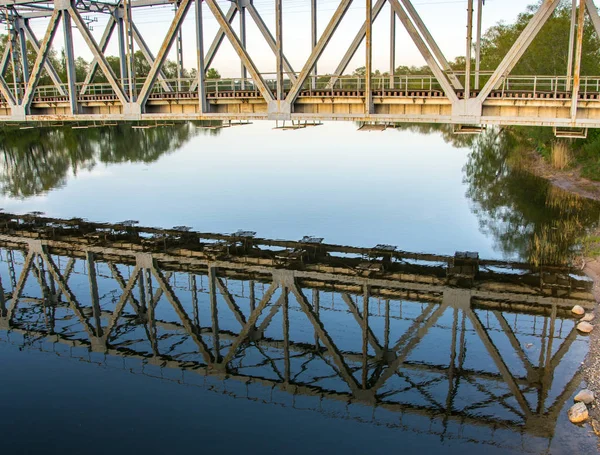 Reflet du pont ferroviaire dans la rivière au coucher du soleil en été . — Photo