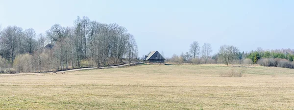 早春の田園地帯の道路沿いの古い納屋で 木はまだ葉がないままです — ストック写真