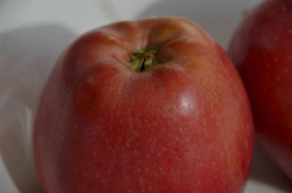 Big ripe red apple close up on white plate