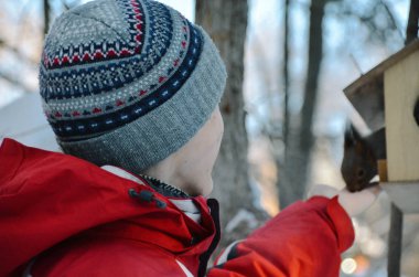 Genç adam renkli bahar ormanında yalak besleme elden bir sincap besler