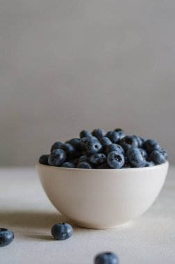 Fildişi kasede koyu gri arka planda taze yaban mersini. Tatlı olgun meyvelerin tazeliği