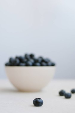 Yabanmersini konsepti: mavi arka planda taze toplanmış tatlı yaban mersini kabının minimalist fotoğrafı.