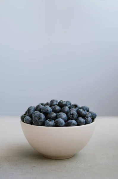 在深蓝色背景的白色碗中新鲜采摘的蓝莓 一捧甜成熟的浆果 — 图库照片