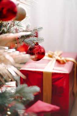 Parlak Noel ağacının altında parlak kırmızı bir kurdeleyle sarılmış büyük bir Noel hediyesi. Sıcak kış tatili. Noel evde.