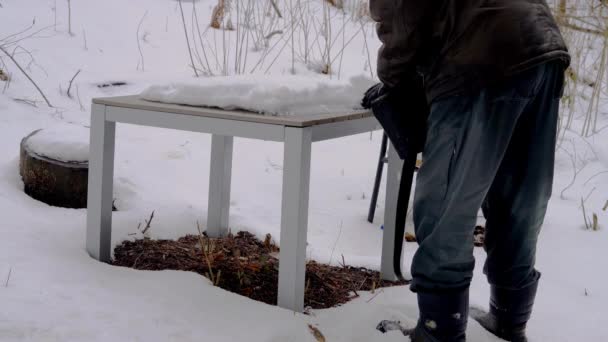 Hombre Limpia Mesa Silla Nieve Madera — Vídeo de stock