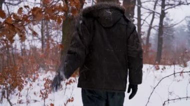 Adam karlı dalları dokunur ve ormanda olur