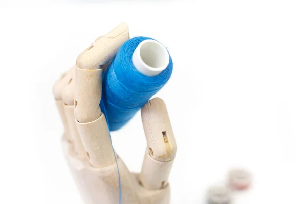 Wooden hand is holding a coil of blue threads — Stock Photo, Image