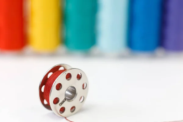 Sewing bobbin and row of spools of thread — Stock Photo, Image