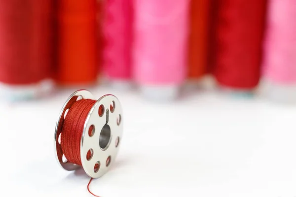 Sewing bobbin and row of spools of thread — Stock Photo, Image