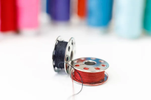 Sewing bobbin and row of spools of thread — Stock Photo, Image