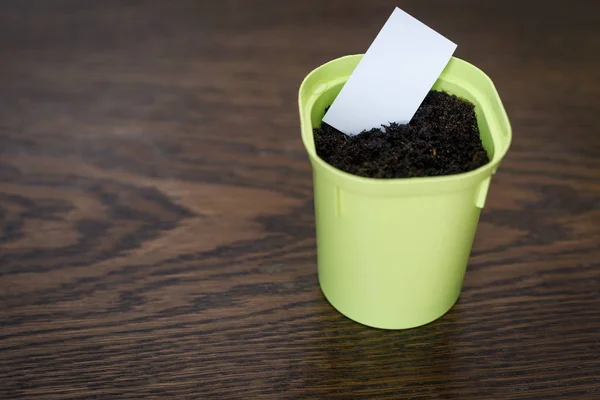 Flower pot with earth and white paper for writing the date and name of the plant — Stock Photo, Image