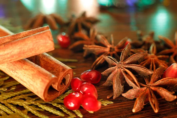 Anise, semillas de granada y palitos de canela en una mesa de madera con retroiluminación colorida. Enfoque selectivo. Fondo para la tarjeta de felicitación de año nuevo — Foto de Stock