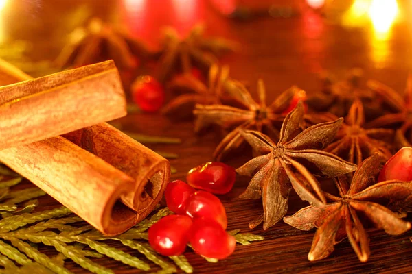 Anise, pomegranate seeds and cinnamon sticks on a wooden table with colorful backlighting. Selective focus. Background for new year greeting card — Stock Photo, Image