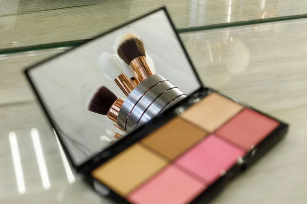 Pincéis de maquiagem são refletidos em um espelho de paleta com sombras — Fotografia de Stock