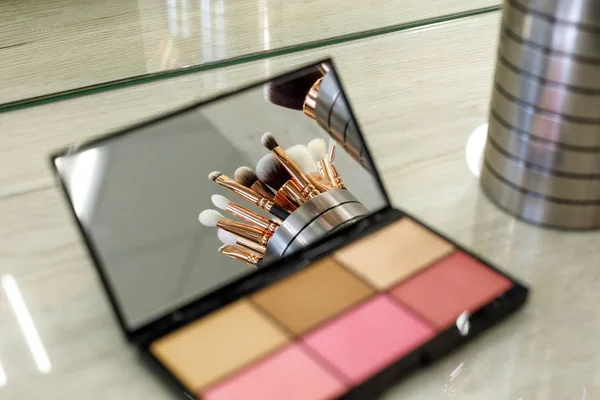 Pinceles de maquillaje se reflejan en un espejo de paleta con sombras — Foto de Stock
