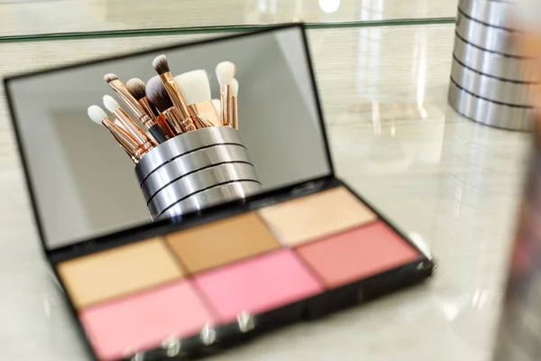 Pinceles de maquillaje se reflejan en un espejo de paleta con sombras — Foto de Stock