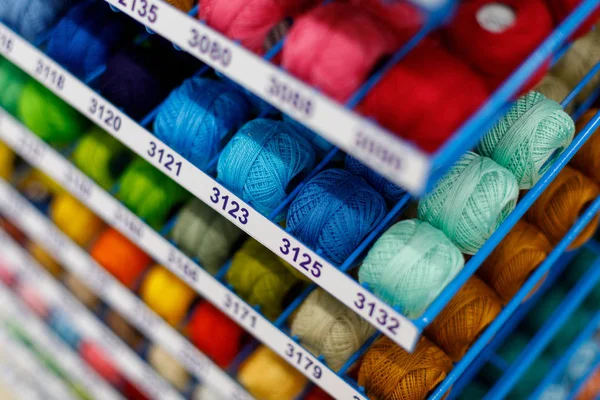 Multi-colored textile threads in hand-made reels are displayed for sale in the store — Stock Photo, Image