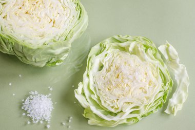 Beyaz lahana dilimi ve açık yeşil arka planda kaba deniz tuzu