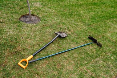 bahçıvan kirli araçları taze haddelenmiş çim üzerinde yatıyor