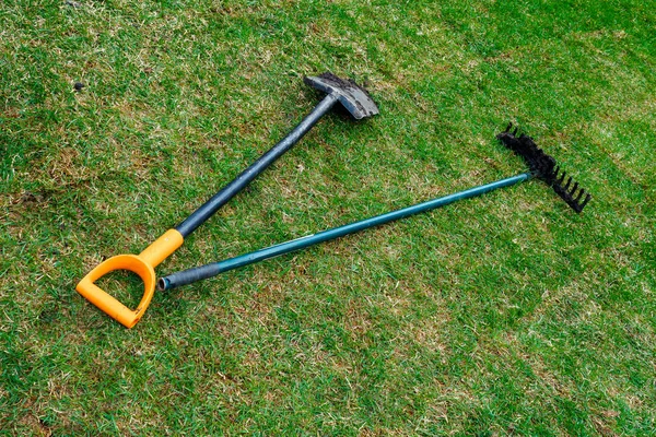 The gardener's dirty shovel and rakes are lying on the fresh rolled lawn — Stock Photo, Image