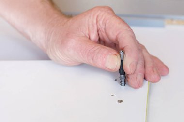 Yaşlı bir adamın eli, mobilya montajı sırasında bağlayıcıyı ayarlar. Yakın plan. Seçici odak