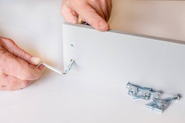 mobilya montajı yaparken mutfak kutusunun şap iki duvar süreci. Vidalardan biri zaten sıkılır, ikincisi erkek elleriyle sıkılır. Close