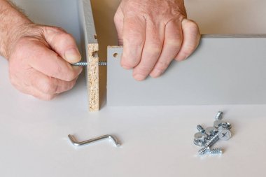 mobilya montajı yaparken mutfak kutusunun şap iki duvar süreci. Vidalardan biri zaten sıkılır, ikincisi erkek elleriyle sıkılır. Close