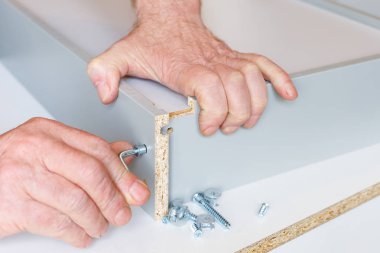 yaşlı bir adamın elleriyle bir mutfak kutusu montaj süreci. Kravat hex anahtar kutusu duvarları