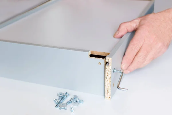 The process of assembling a kitchen box by the hands of an elderly man. Tie hex key box walls — Stock Photo, Image