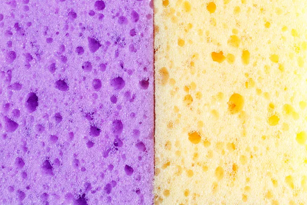 Spugne colorate per il lavaggio dei piatti e altre esigenze domestiche. Vista dall'alto. Texture di due spugne viola e gialle, gommapiuma . — Foto Stock