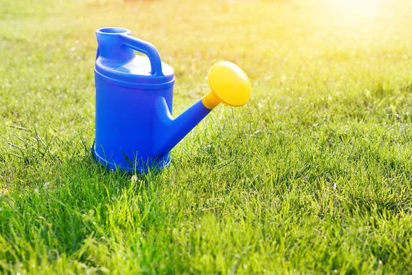 Mavi plastik sulama yeşil bir çim üzerinde sarı bir lens ile olabilir — Stok fotoğraf