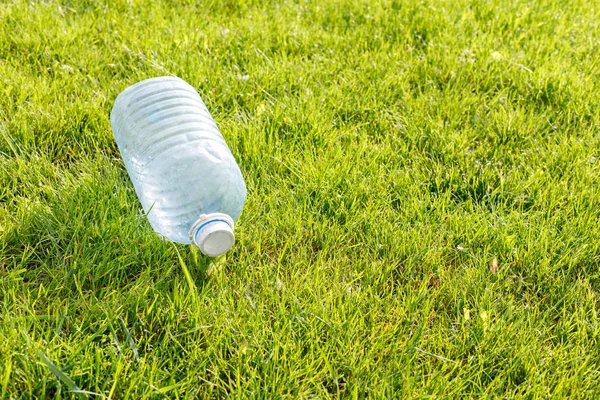 Empty plastic bottle on a green lawn. Concept: environmental pollution — Stock Photo, Image