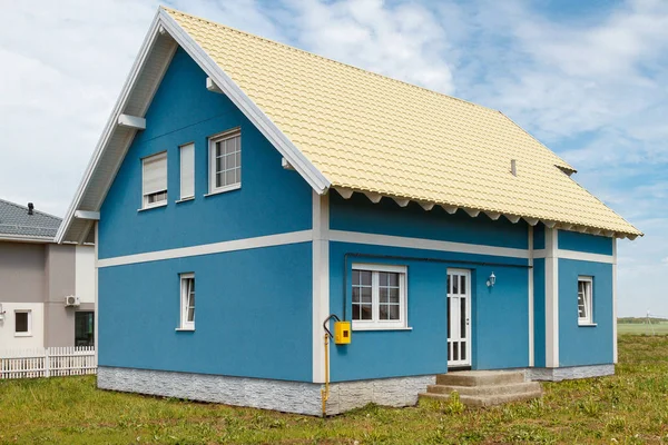 A small blue house with white windows and a light yellow metal roof. — Stock Photo, Image