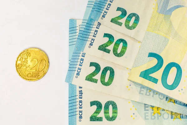 Varios billetes de 20 euros y una moneda de 20 centavos. El concepto de oponerse a las ganancias grandes y pequeñas, ahorrar o gastar dinero . — Foto de Stock