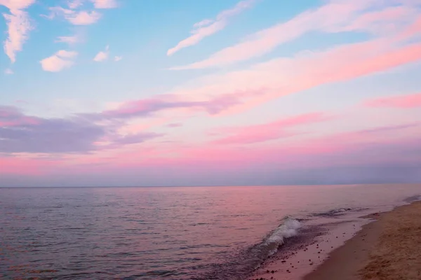 Hermoso atardecer nublado y paisaje marino. Cielo rosado y azul reflejado en el agua oscura por la noche — Foto de Stock