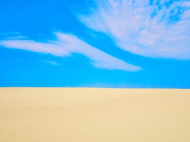 Güneşli bir yaz gününde kum tepeleri üzerinde küçük bir bulut ile yüksek mavi gökyüzü. Curonian Spit UNESCO Dünya Mirası Listesi 'nde yer almaktadır. Isı kavramı. Arka plan.