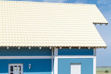 mavi gökyüzüne karşı mavi bir evde bej metal çatı