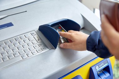 A female hand dials a personal code on the ATM keyboard. The concept of safe use of bank cards, deductible funds, the wholesale of services and goods, receiving cash. Close-up clipart