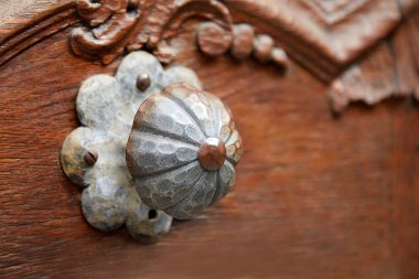 Terk edilmiş bir evde ahşap bir kapıüzerinde eski metal saplı. Yuvarlak şekil bir çiçeğe benzer. Bu konuda üzerinde küçük pas izleri var. Ev dekorasyonu. Seçici odaklama