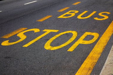 Asfaltta sarı boya olan otobüs durağı tabelası. Beklentilerin sembolü, hayatın anlamını yeniden düşünmek, nihai yol, geleceğe giden yol.