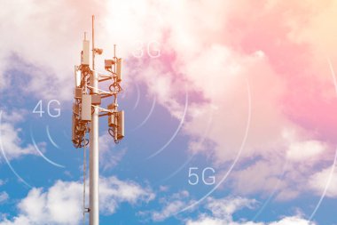 Telekomünikasyon kulesi 4G, 5G vericili. Telekomünikasyon kulesinde, pembe-sarı bulutlu mavi gökyüzü üzerinde verici antenleri olan bir baz istasyonu. Renkli