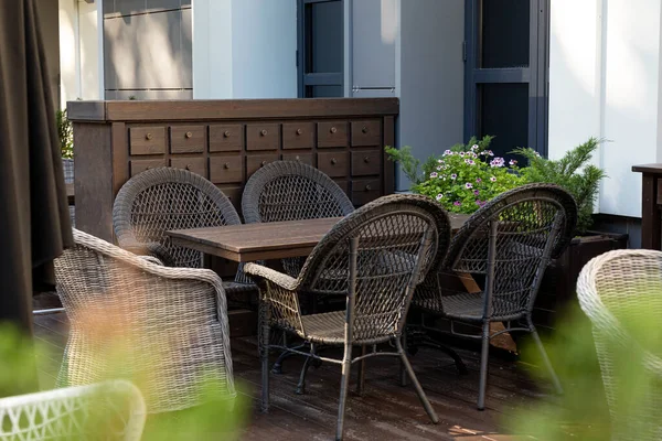 Empty wooden table and wicker chairs in an outdoor cafe awaiting the first visitors after quarantine during the COVID-19 pandemic