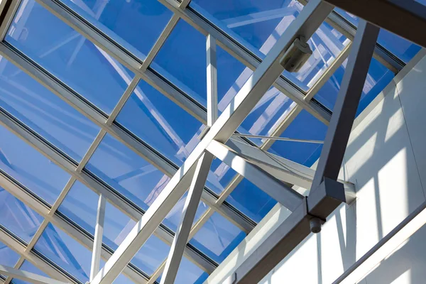 Mavi gökyüzüne karşı bir deponun, alışveriş merkezinin ya da ofis merkezinin çelik çerçevesi. Tavanlar hareket kabiliyeti ve sertliği korumak için cıvatalar ve kaynaklarla birbirine bağlı metal kirişlerden yapılmış..