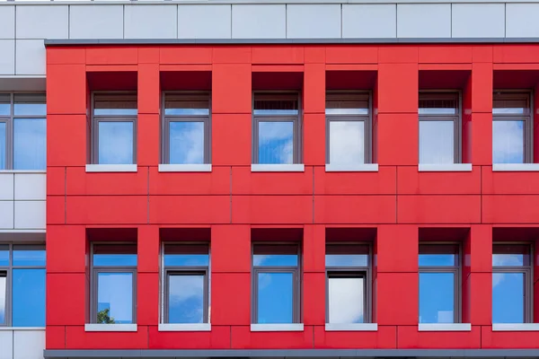 Een rij ramen op een rode geventileerde gevel. Deel van de muur van een gekleurd gebouw om een levendige stedelijke ruimte weer te geven — Stockfoto