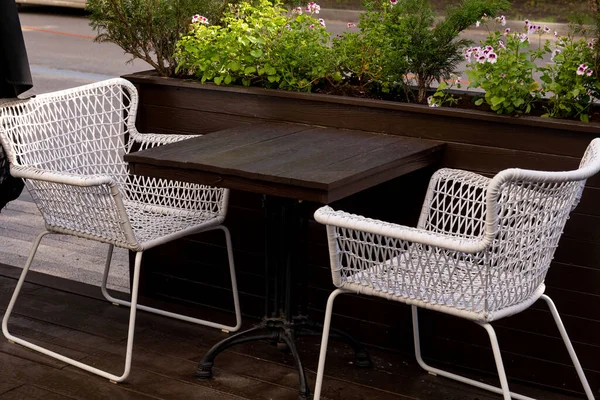 Empty wooden table and white wicker chairs in an outdoor cafe, waiting for the first visitors after quarantine was completed during the COWID-19 pandemic — Stock Photo, Image